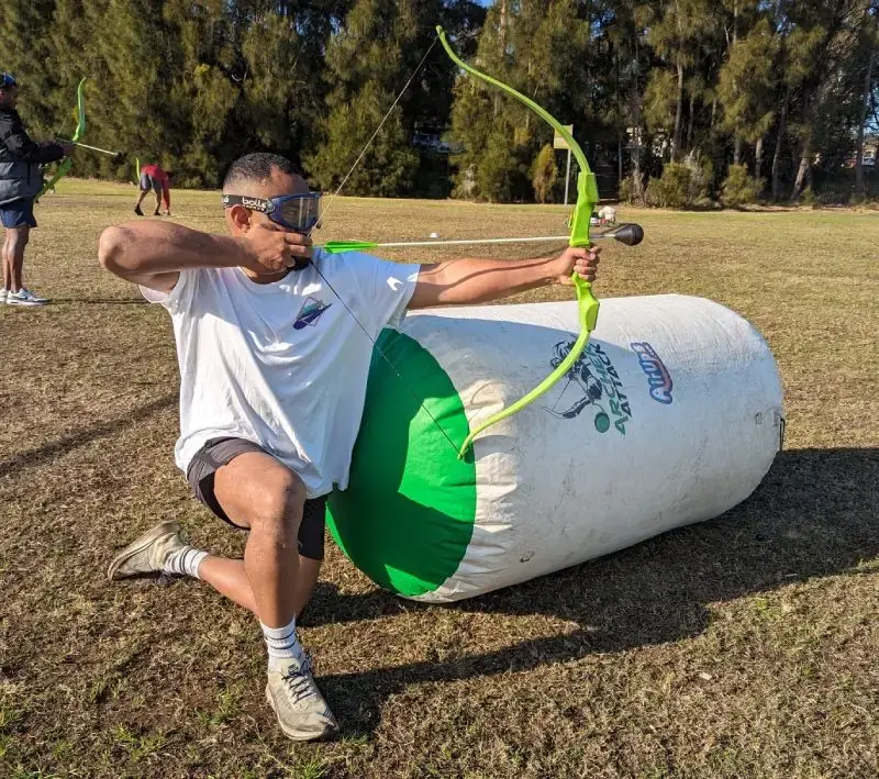 Battle Archery players fire foam-tipped arrows during an outdoor mission setup.